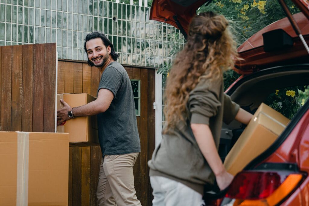 pexels photo 4246266 Cheerful modern male and female in comfortable casual clothes unpacking car trunk in green garden of new house while moving in together
