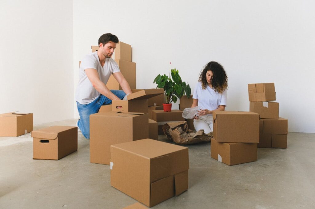 pexels photo 7204019 Serious couple opening brown large carton boxes with different belongings on floor at home